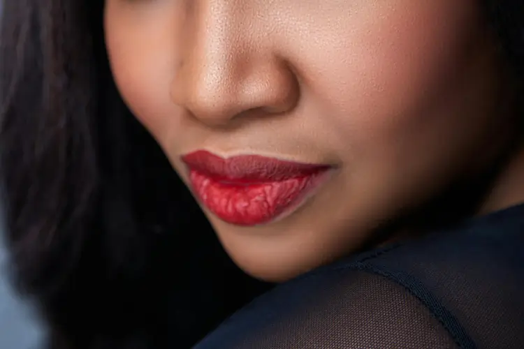 Chica de piel oscura con labios rojos carnosos. La foto está recortada por debajo de los ojos, que no se ven