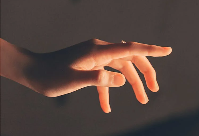 Mano iluminada por luz tenue trata con Radiesse